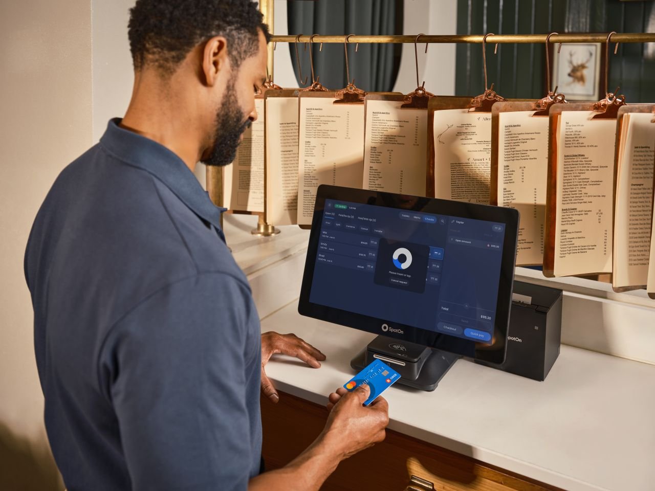 Home A restaurant staff member uses a POS system to process a credit card payment at the counter.
