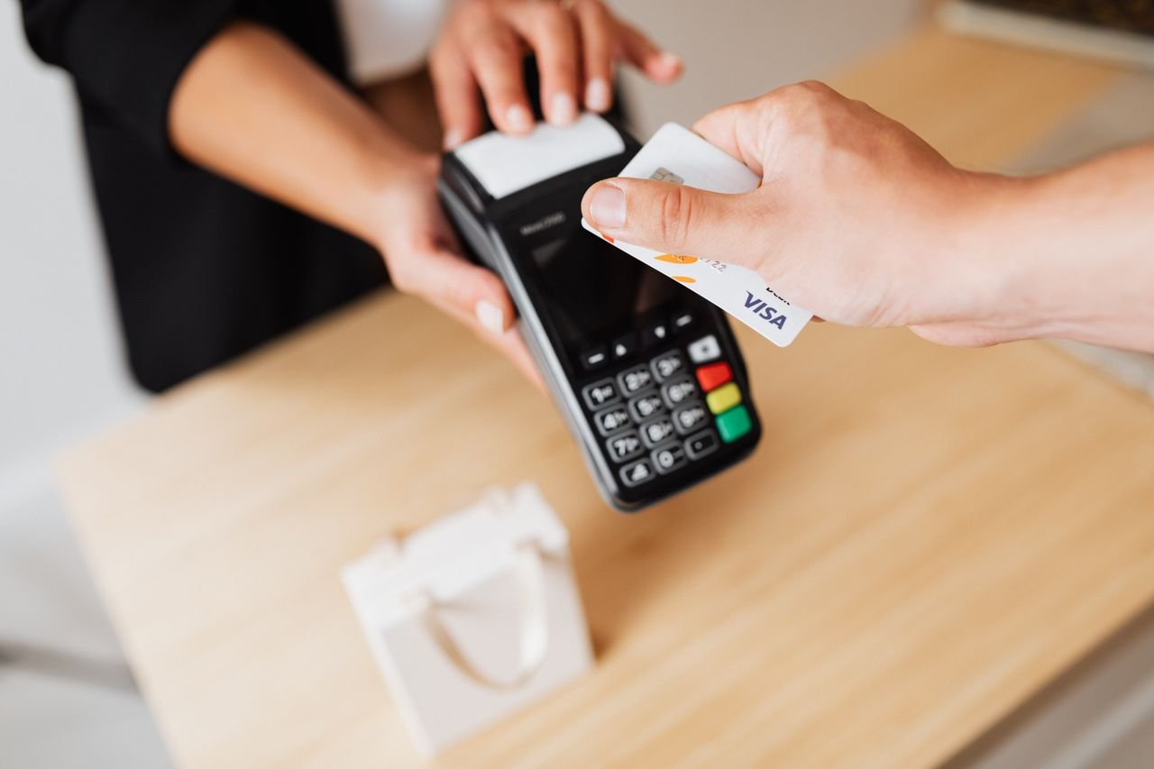 Home Close-up of hands using a contactless payment terminal with a credit card indoors.
