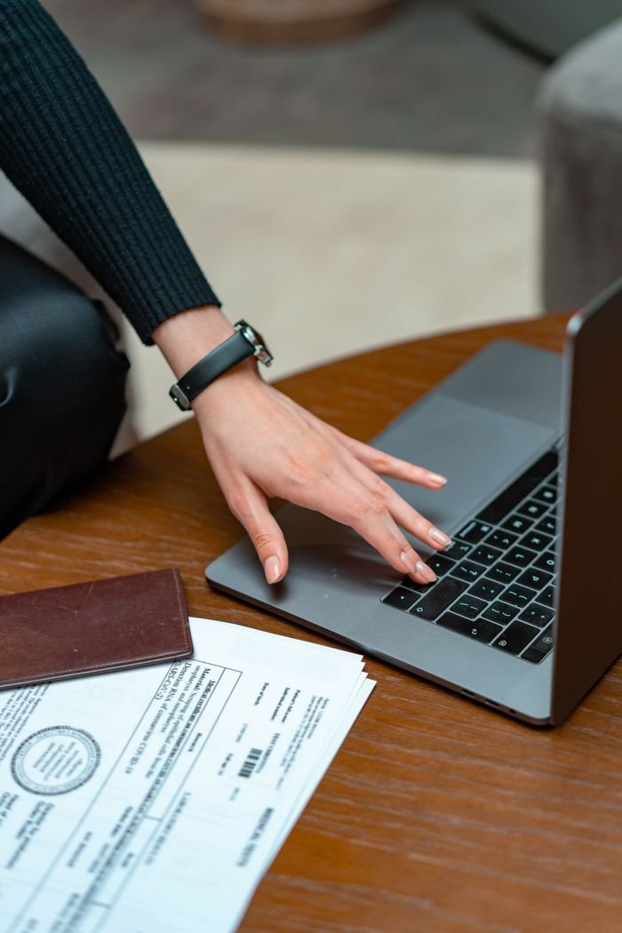 Contact Close-up of a person typing on a laptop with legal documents on a table, showcasing work and technology integration.