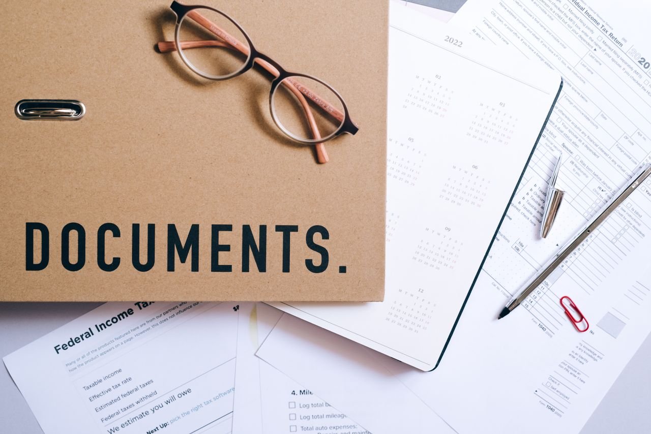 Contact Flat lay of office supplies including documents, calendar, and eyeglasses on a desk.