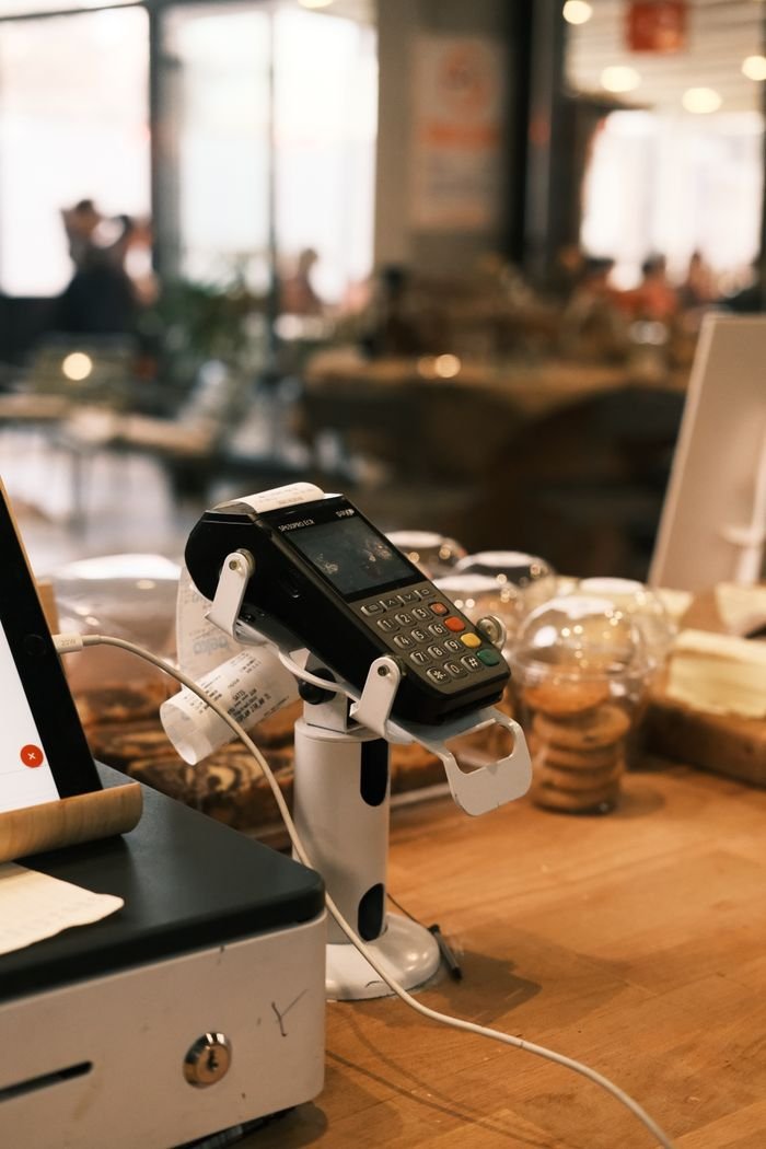 A digital payment terminal on a cozy café counter, suggesting a modern lifestyle.